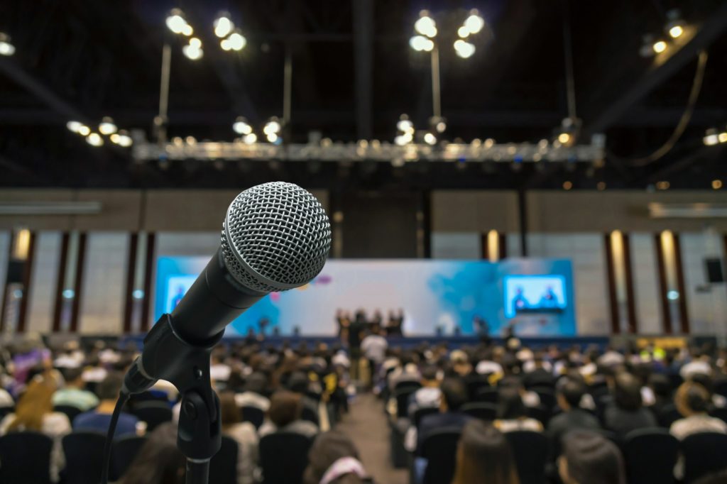 Microphone with Abstract blurred photo of conference hall or meeting room with attendee background